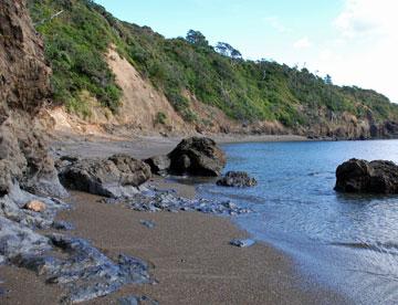 A stony black sand beach is our first stop