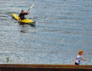 Dad kayaking with daughter looking on